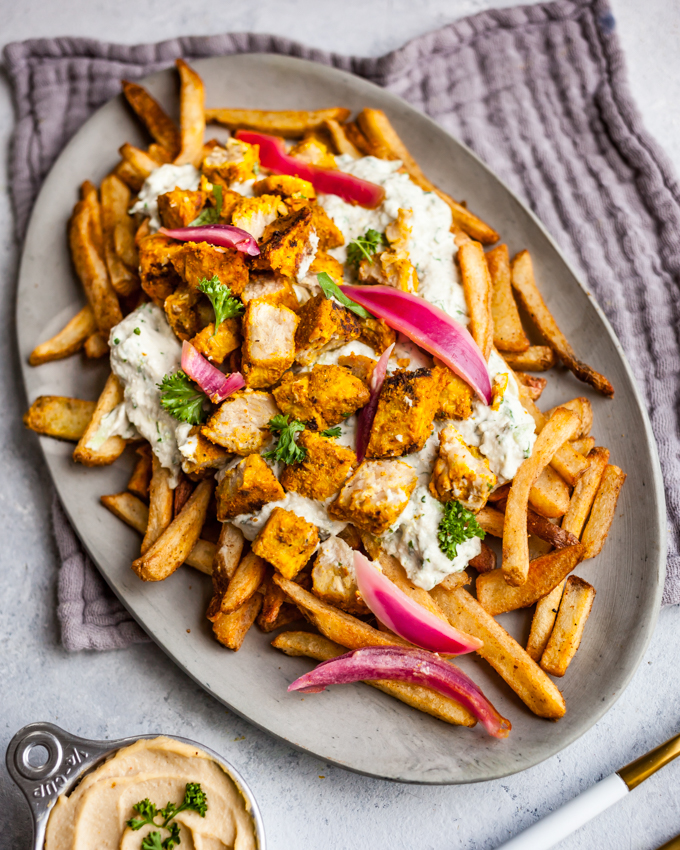 AMAZING seasoned fries topped with vegan 'chicken' shawarma and creamy sunflower tzatziki | Perfect game day appetizer recipe #plantbased #vegan